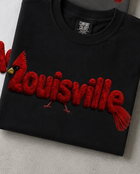 Louisville Cardinal feather-lettering tee — Black Comfort Colors, folded
