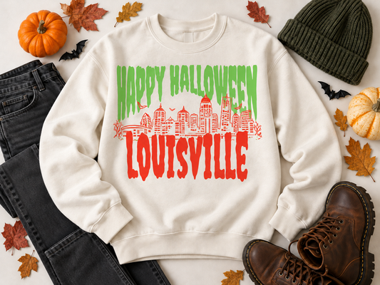 Louisville Halloween Spooky Skyline crewneck in Ivory — green drip HAPPY HALLOWEEN over orange Louisville skyline and LOUISVILLE lettering — flat lay with pumpkins, fall leaves, black jeans, boots and bats