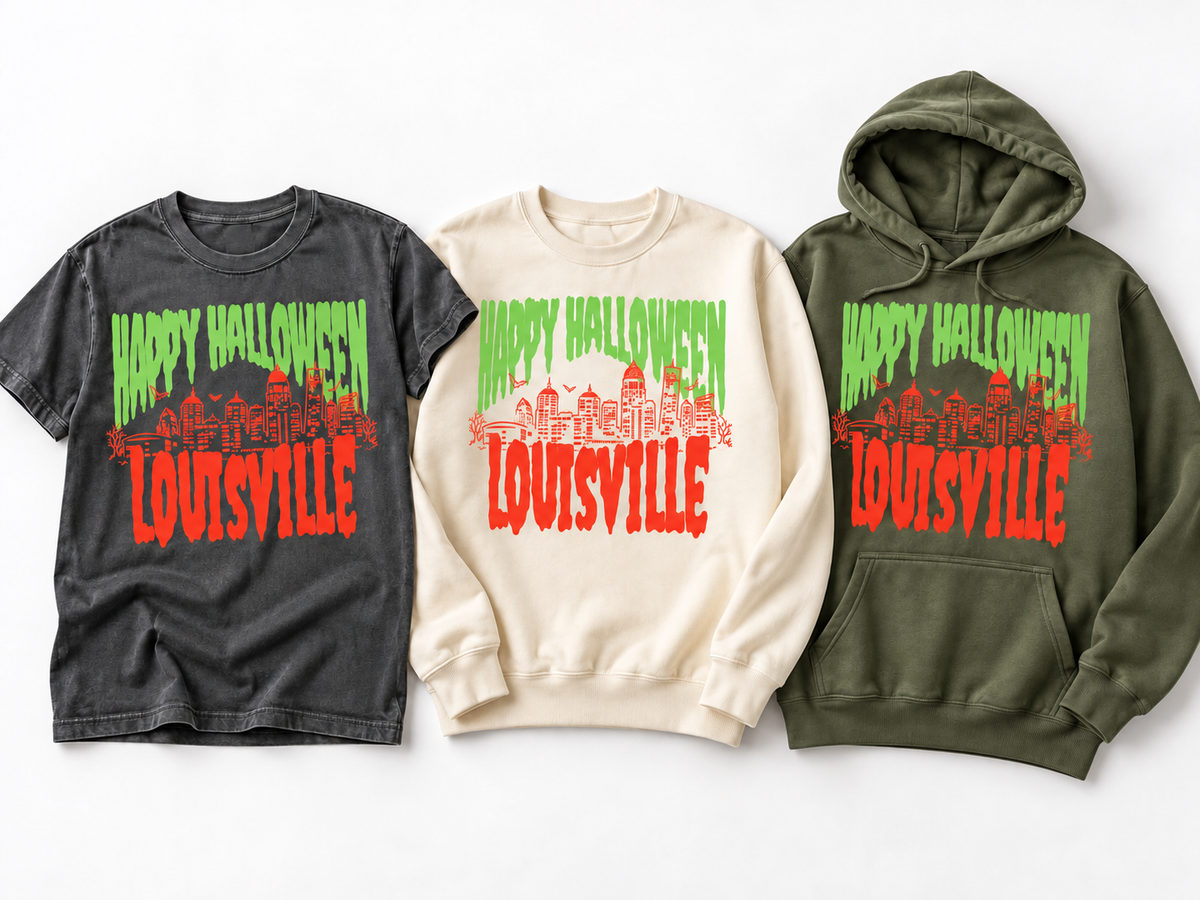 Louisville Halloween Spooky Skyline hanging trio — Pepper Comfort Colors tee, Ivory crewneck sweatshirt and Moss hoodie — green drip HAPPY HALLOWEEN and orange LOUISVILLE skyline graphic
