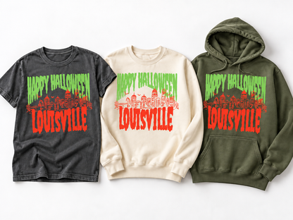 Louisville Halloween Spooky Skyline hanging trio — Pepper Comfort Colors tee, Ivory crewneck sweatshirt and Moss hoodie — green drip HAPPY HALLOWEEN and orange LOUISVILLE skyline graphic